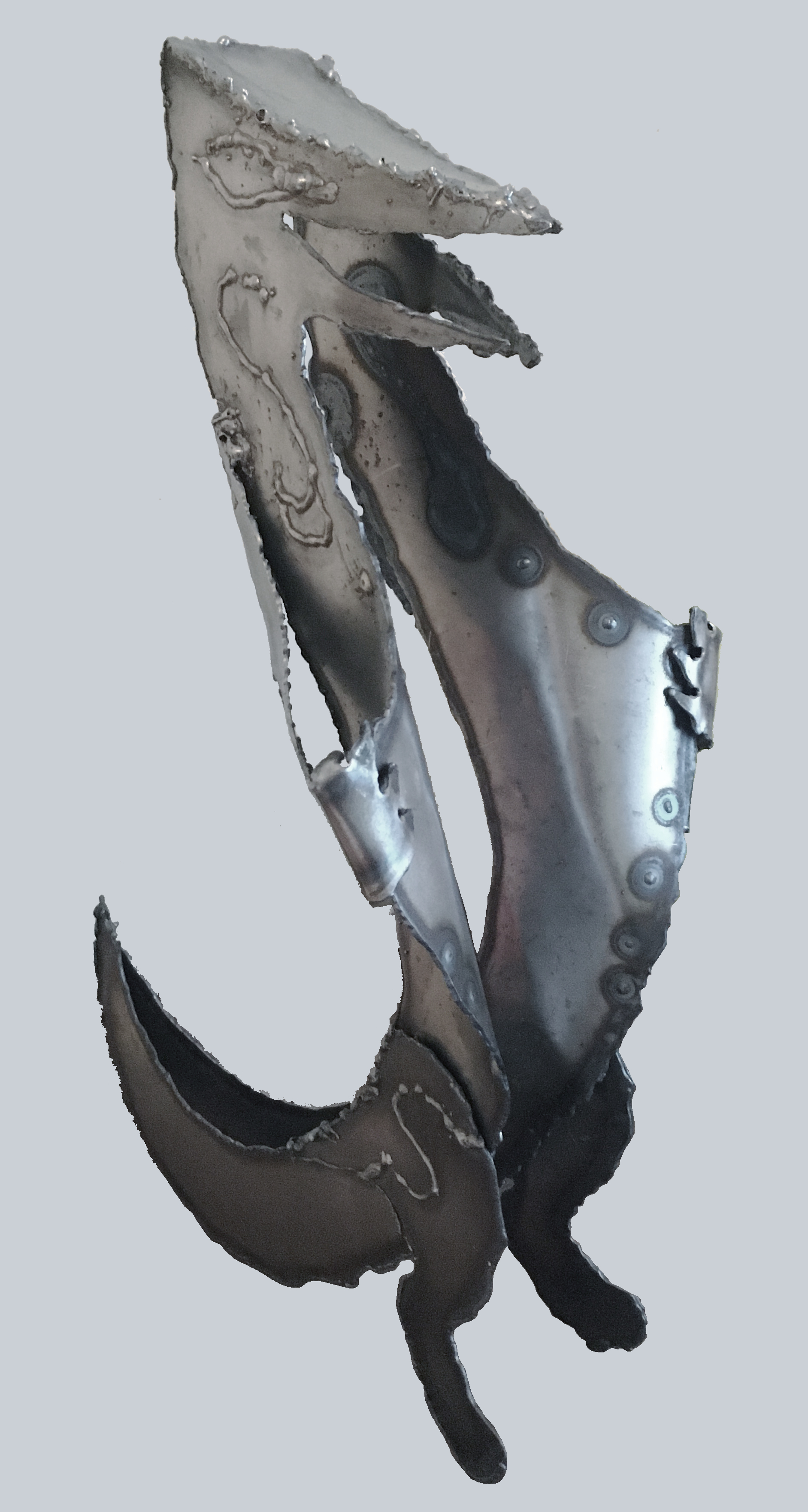 An image of a metal sculpture. It is a creature standing on two legs and opening its body in two while looking pleased. It is made of metal sheets welded together. The metal sheets have rough melted edges.